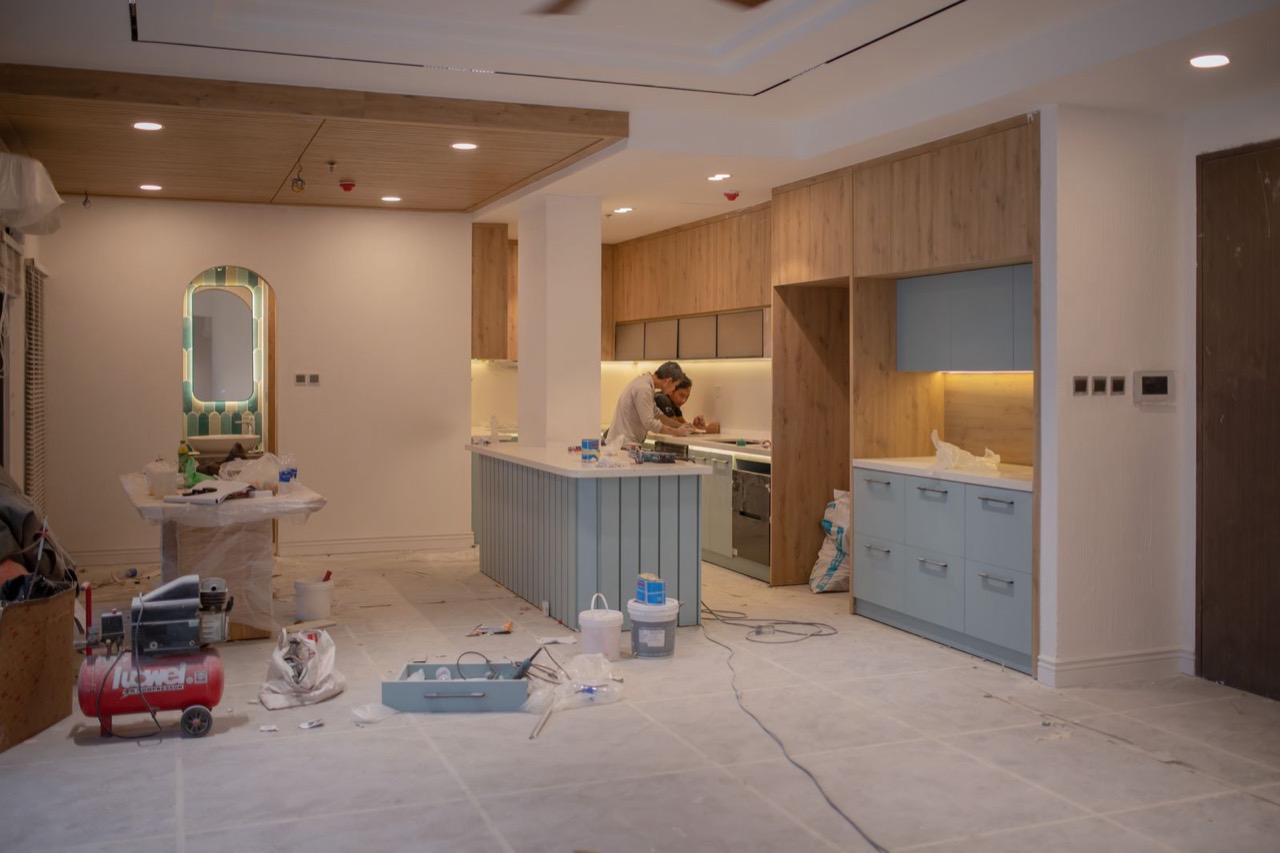 Two workers fitting kitchen cabinets and a countertop in a kitchen still under renovation