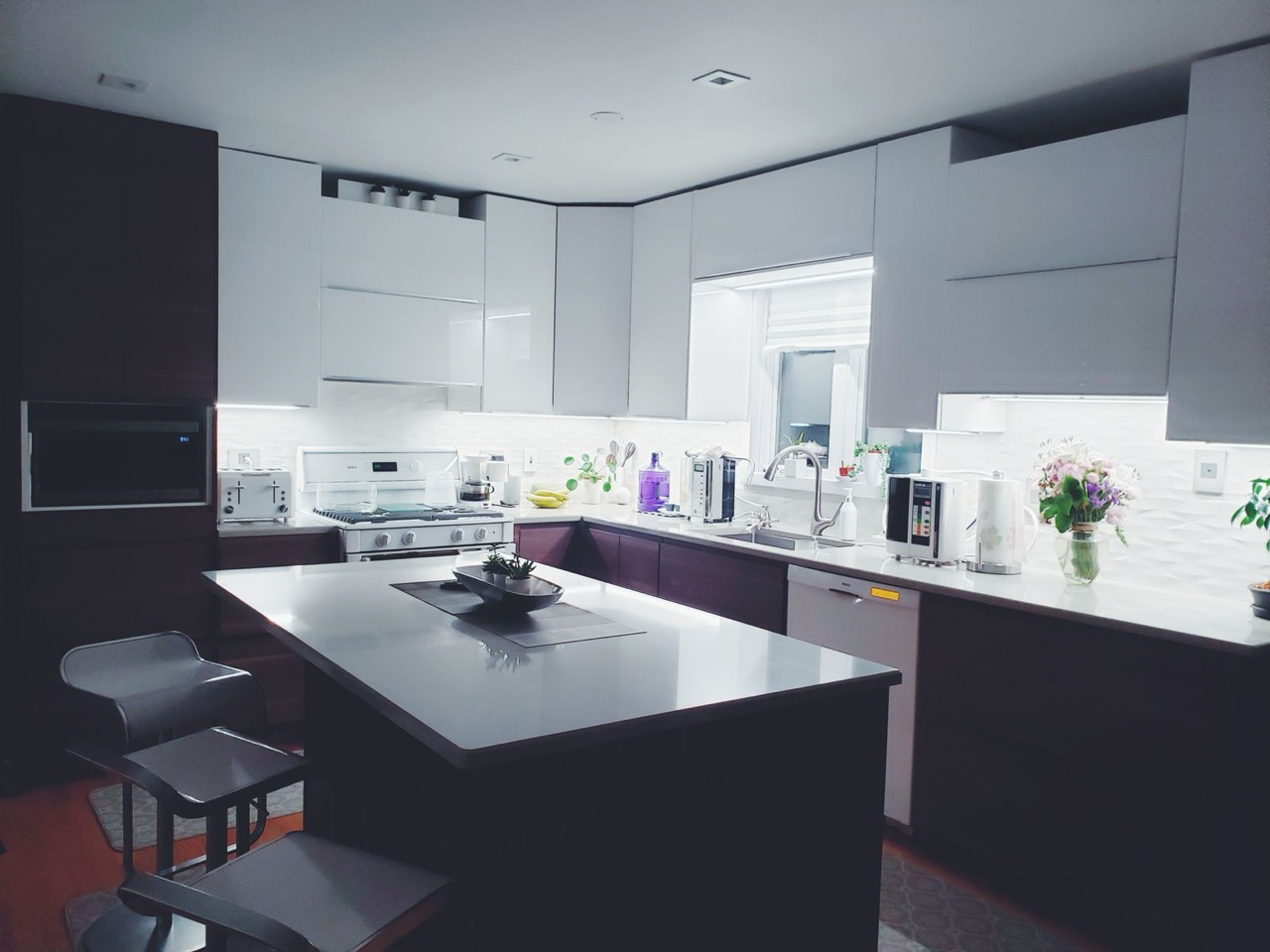 Kitchen with white upper cabinets, dark lower cabinets and a central island with stools